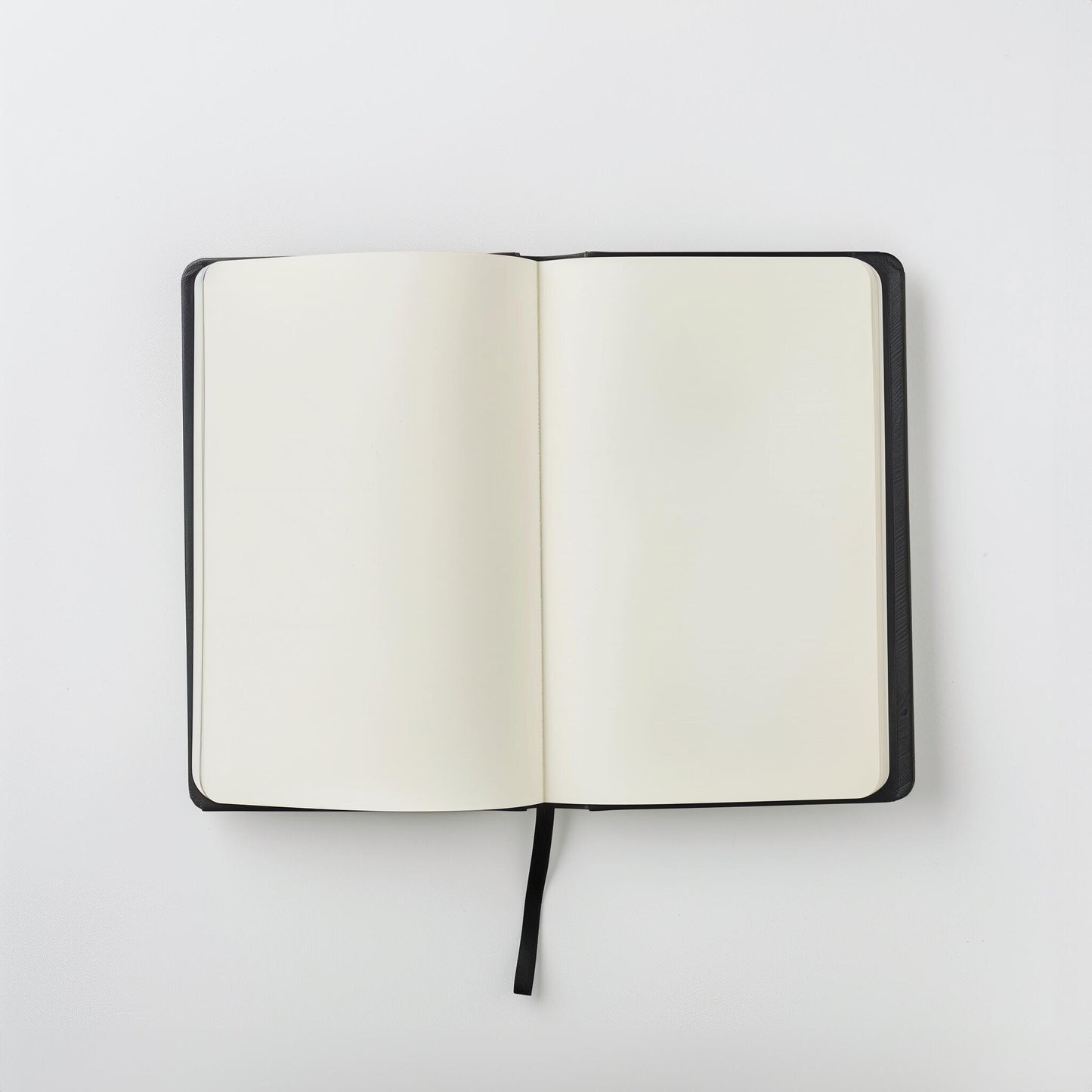 The Example product is an open black notebook with blank white pages and a black ribbon bookmark, shown from above on a plain white background.