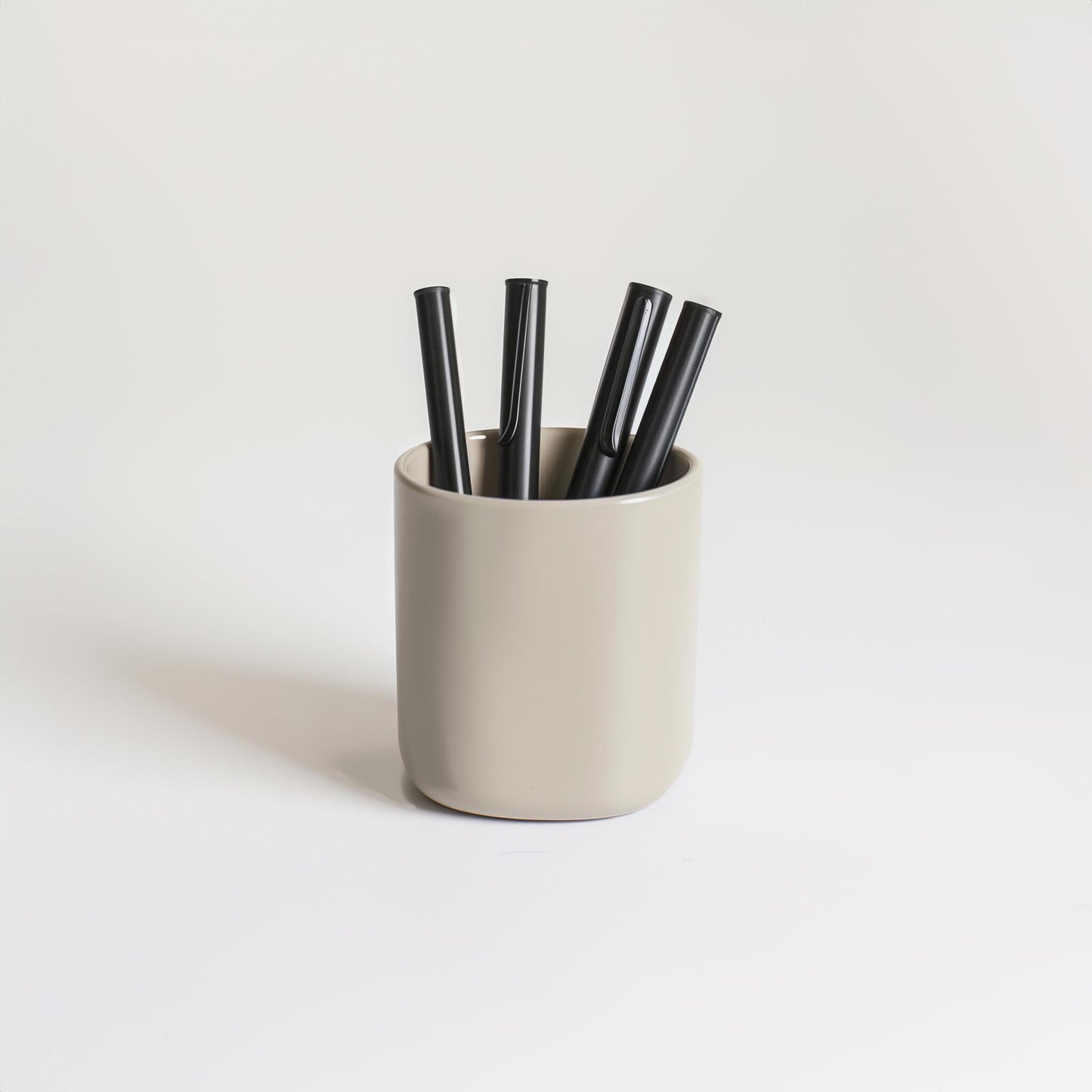 The Example product features a beige cup containing four black pens, set on a plain white surface with a light background.