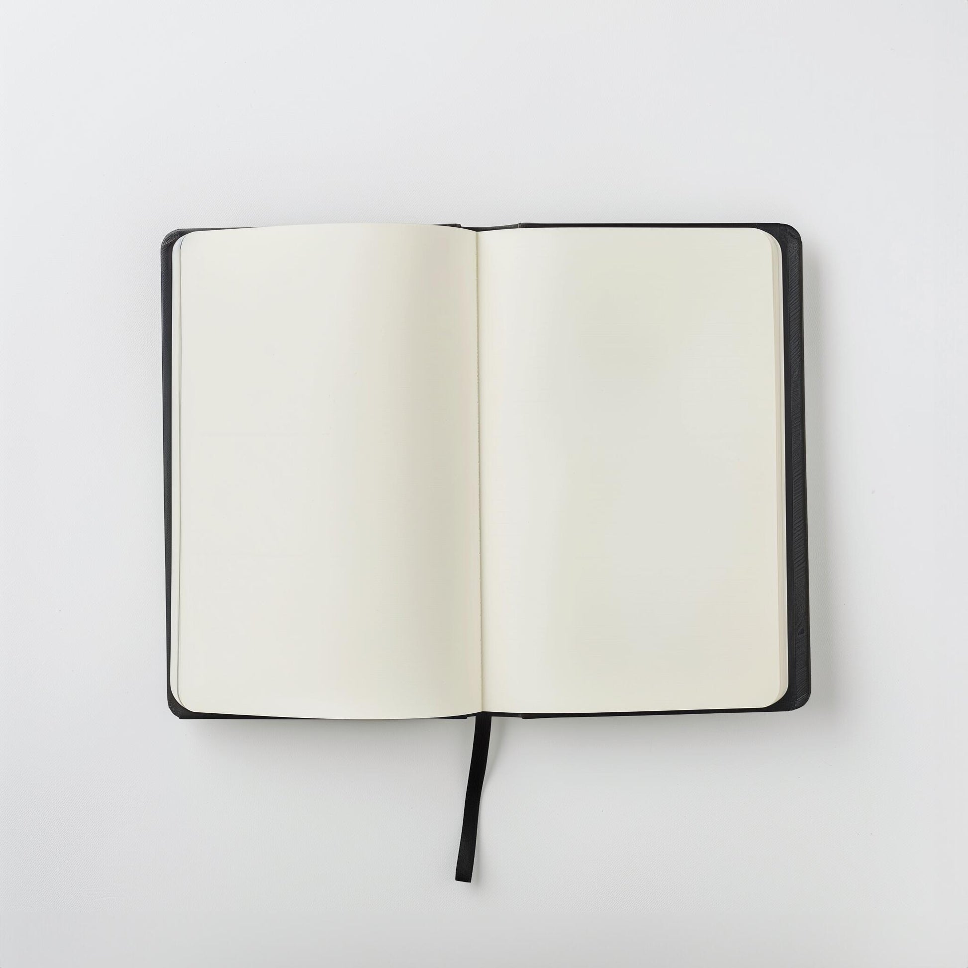 The Example product is an open black notebook with blank white pages and a black ribbon bookmark, shown from above on a plain white background.