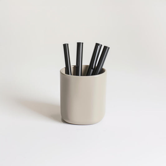 The Example product features a beige cup containing four black pens, set on a plain white surface with a light background.