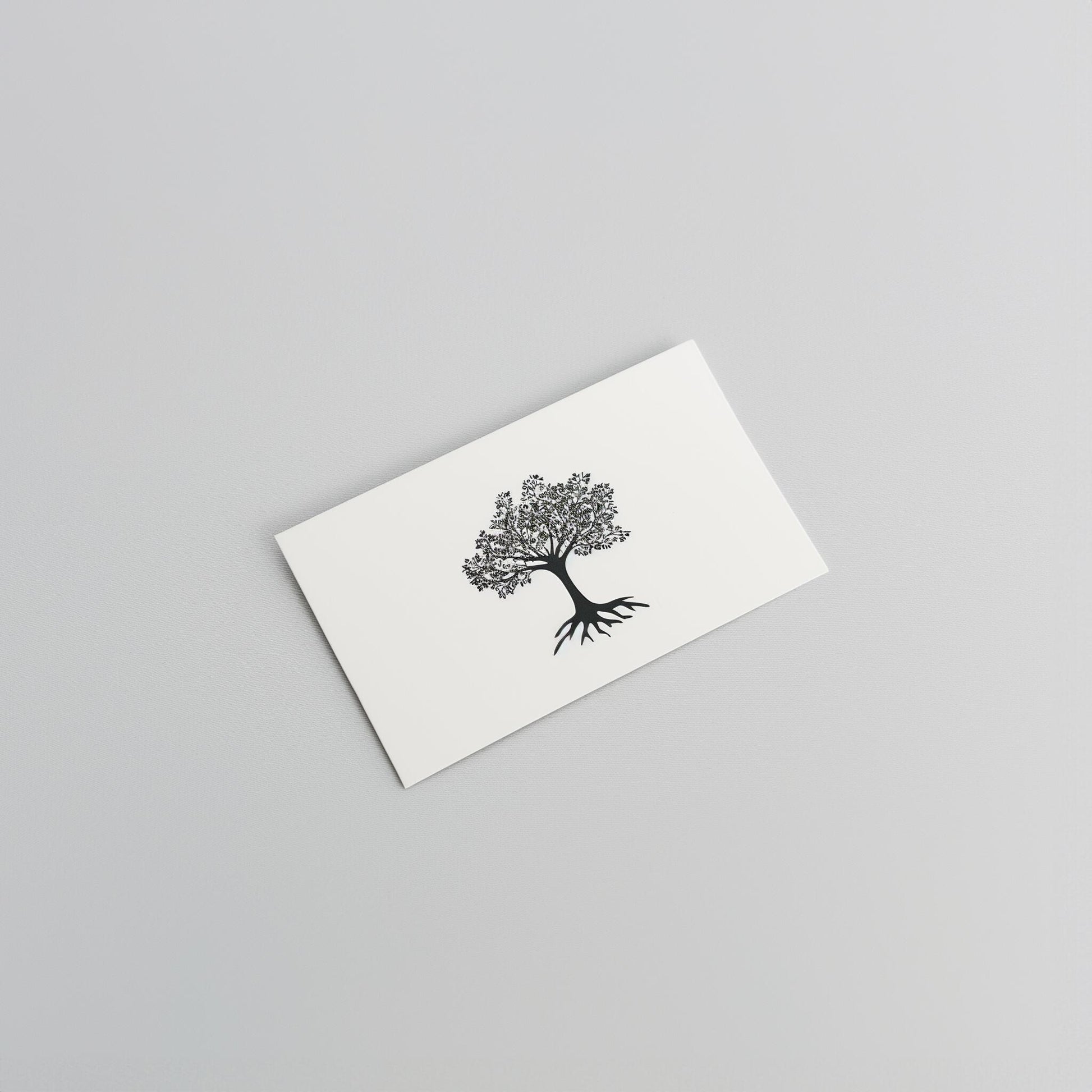 A white Example product card with a minimalist black tree and exposed roots illustration, displayed on a plain light gray surface.
